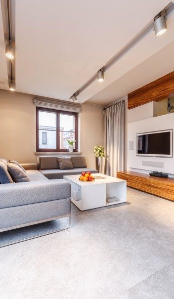 Modern living room with a grey sofa, a white coffee table, and a wooden TV accent wall.