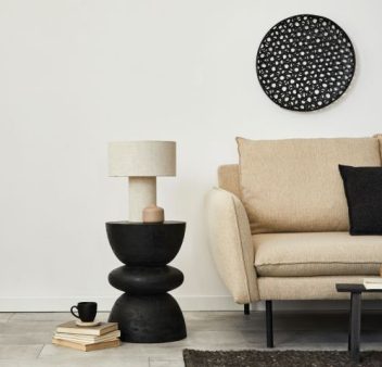 Modern interior featuring a beige armchair, a black side table with a lamp, and circular black wall art.
