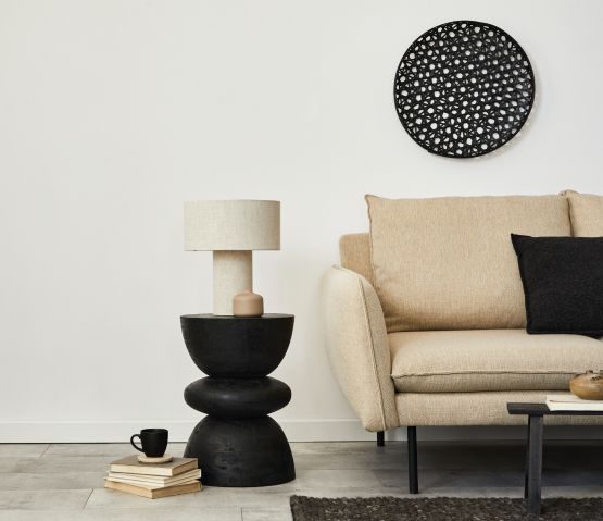 Modern interior featuring a beige armchair, a black side table with a lamp, and circular black wall art.