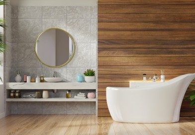 Modern bathroom featuring a freestanding white bathtub, a wooden accent wall, and a round mirror over the sink.